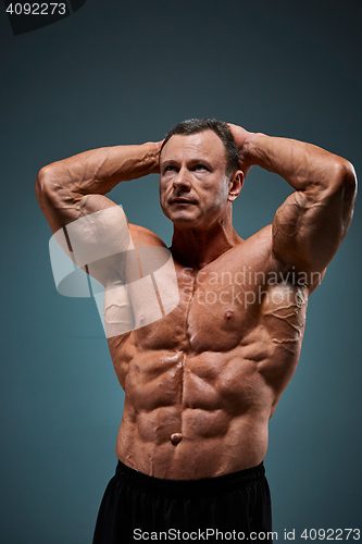 Image of torso of attractive male body builder on gray background.