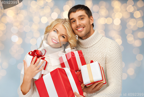 Image of happy couple with christmas gifts over lights