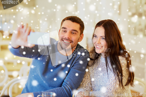 Image of couple taking smartphone selfie at cafe restaurant