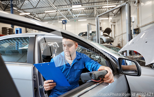 Image of mechanic man with diagnostic scanner at car shop