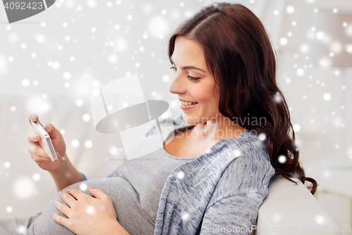 Image of happy pregnant woman with smartphone at home