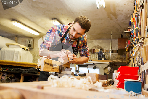 Image of carpenter working with plane and wood at workshop