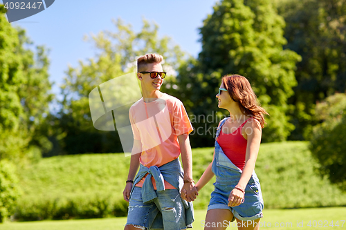 Image of happy teenage couple walking at summer park