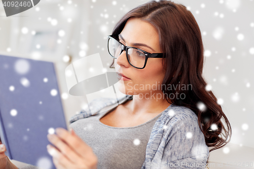 Image of young woman in glasses reading book at home