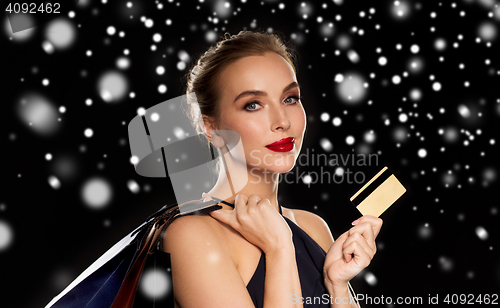 Image of woman with credit card and shopping bags over snow