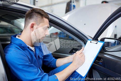 Image of auto mechanic man with clipboard at car workshop