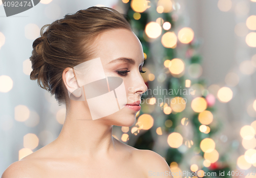 Image of beautiful young woman face over christmas lights