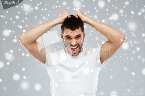 Image of crazy shouting man in t-shirt over snow background