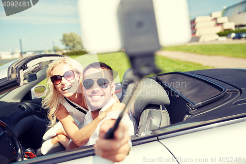 Image of happy couple in car taking selfie with smartphone