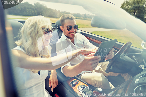 Image of happy couple with tablet pc in cabriolet car