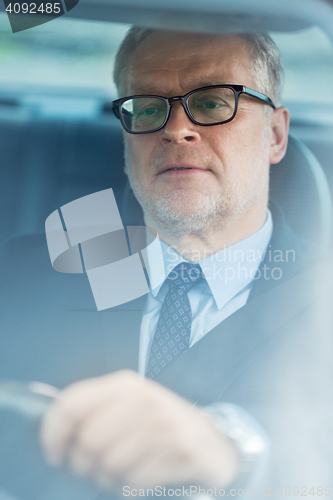 Image of senior businessman driving car