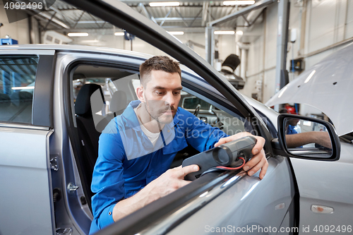 Image of mechanic man with diagnostic scanner at car shop