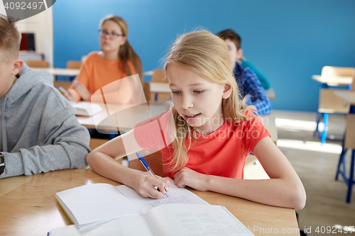 Image of student girl with book writing school test