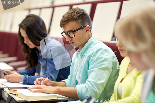 Image of group of students with books writing at lecture