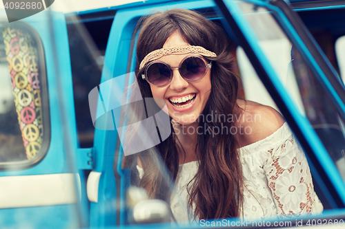 Image of smiling young hippie woman in minivan car