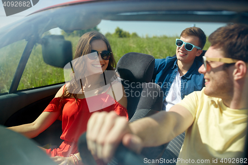 Image of happy friends driving in cabriolet car