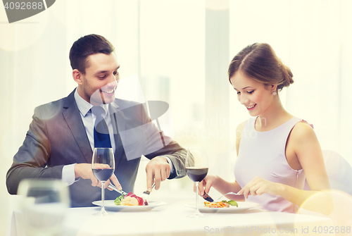 Image of smiling couple eating main course at restaurant