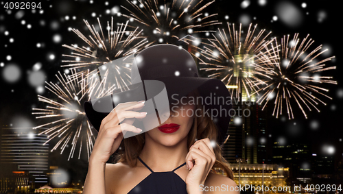 Image of beautiful woman in black hat over night firework
