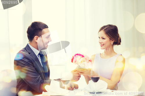 Image of smiling man giving flower bouquet at restaurant