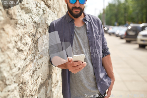 Image of close up of man with smartphone at stone wall