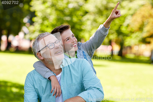 Image of grandfather and boy pointing finger at summer park