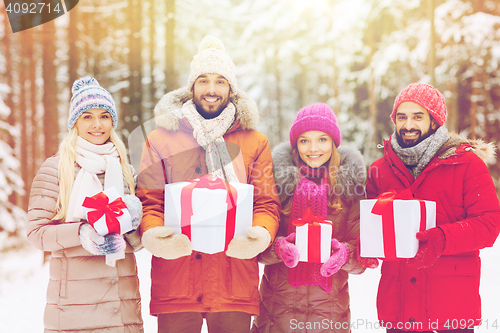 Image of happy friends with gift boxes in winter forest