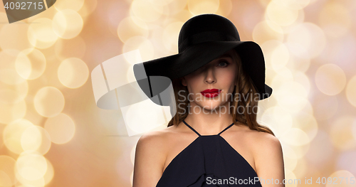 Image of beautiful woman in black hat over holidays lights