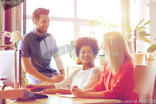 Image of happy creative team talking in office