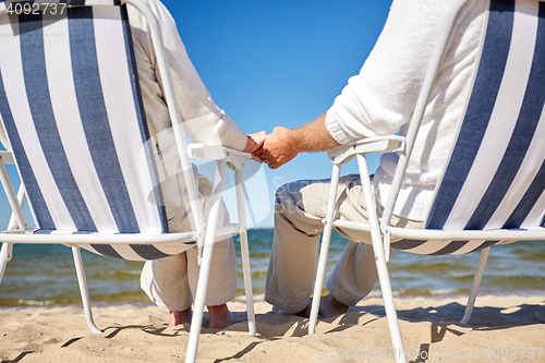 Image of senior couple sitting on chairs at summer beach