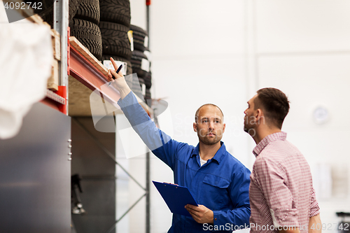 Image of auto mechanic with clipboard and man at car shop