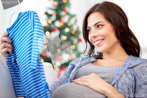 Image of happy woman holding baby boys bodysuit at home