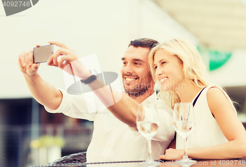 Image of happy couple taking selfie with smartphone at cafe