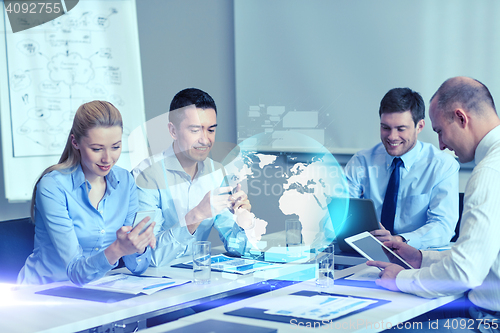 Image of smiling business people with gadgets in office