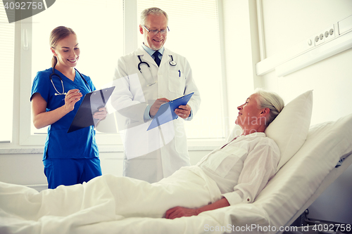 Image of doctor and nurse visiting senior woman at hospital