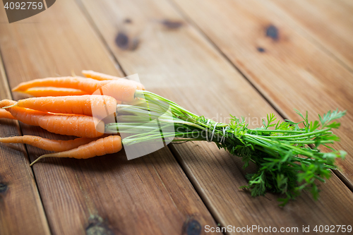 Image of close up of carrot bunch on wooden table