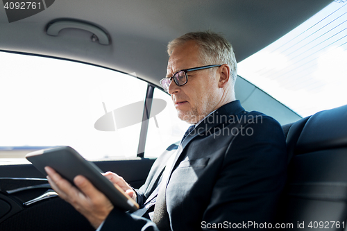 Image of senior businessman with tablet pc driving in car