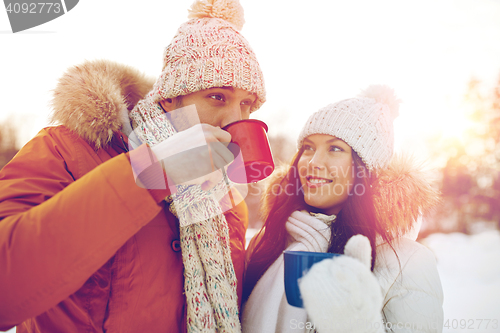 Image of happy couple with tea cups over winter landscape