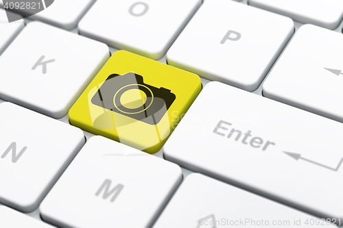 Image of Tourism concept: Photo Camera on computer keyboard background