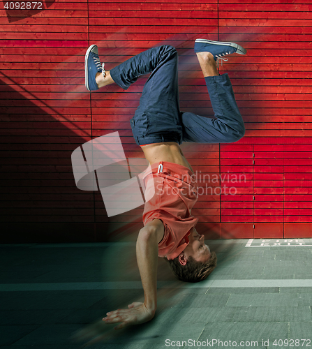 Image of Break dancer doing handstand against colorful wall background