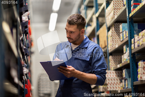 Image of auto mechanic with clipboard at car workshop