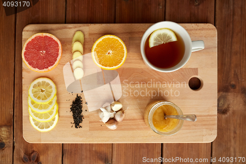 Image of ginger tea with honey, citrus and garlic on wood