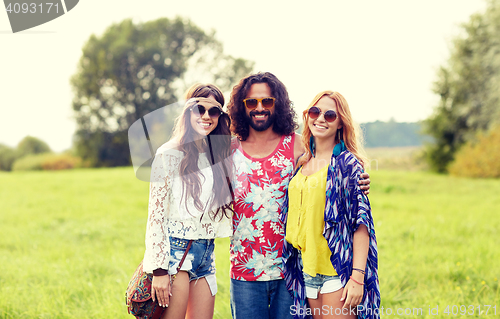 Image of smiling young hippie friends on green field