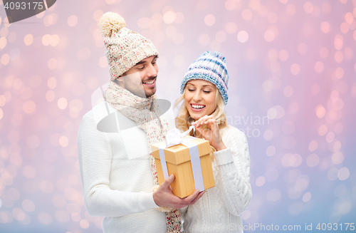 Image of smiling couple in winter clothes with gift box