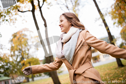 Image of beautiful happy young woman walking in autumn park