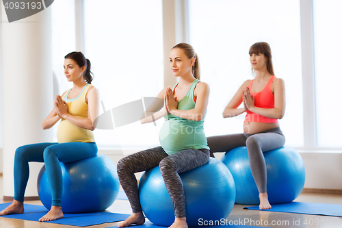 Image of happy pregnant women exercising on fitball in gym