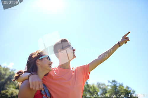 Image of happy couple pointing finger at summer park