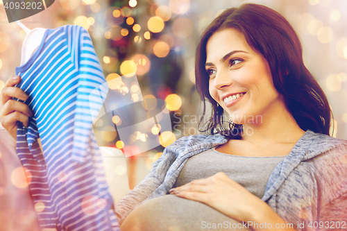 Image of happy woman holding baby boys bodysuit at home