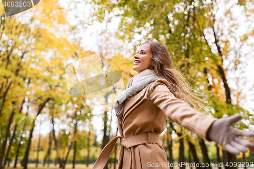 Image of beautiful happy young woman walking in autumn park