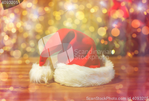 Image of close up of santa hat on wooden table over lights