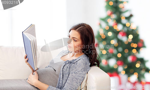 Image of pregnant woman reading book at home